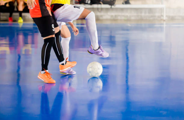 il giocatore di futsal intrappola e controlla la palla per sparare in porta. calciatori che si combattono l'un l'altro calciando la palla. palazzetto dello sport indoor - futsal indoors soccer ball soccer foto e immagini stock