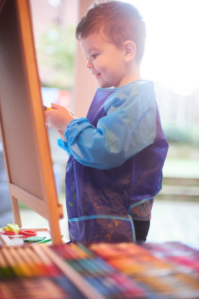 istock Smiling toddler painting at easel 1133892794