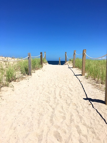 Sandy Beach walkway with Atlantic Ocean in background with some clouds and beach grass at Cape Code  (Sandwich, MA - 2018)