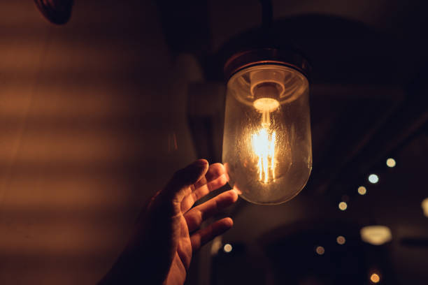 Hand reaching for a vintage light bulb. stock photo