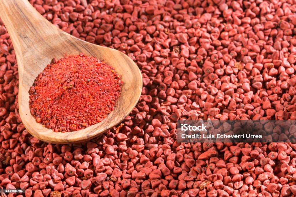 Achiote seeds and powder in the spoon - Bixa orellana Bowl Stock Photo