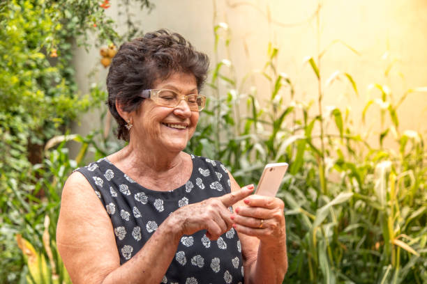 happy elderly woman using cellphone happy elderly woman using cellphone hispanic grandmother stock pictures, royalty-free photos & images