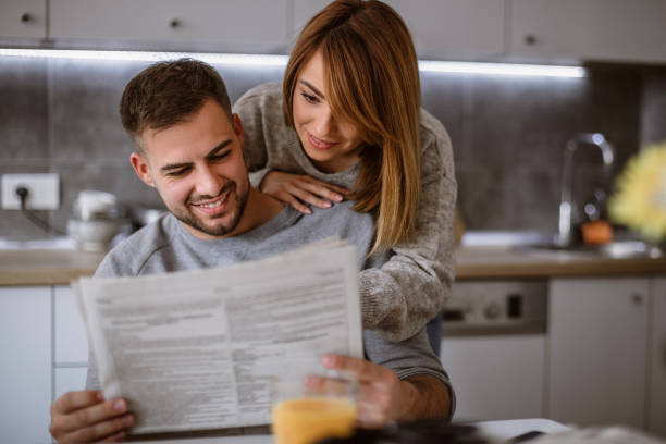 couple reading newspaper at home - reading newspaper 30s adult imagens e fotografias de stock