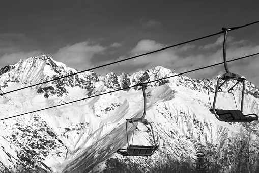 Chairlift on ski resort and snowy mountains at nice sunny day. Caucasus Mountains in winter. Hatsvali, Svaneti region of Georgia. Black and white toned landscape.