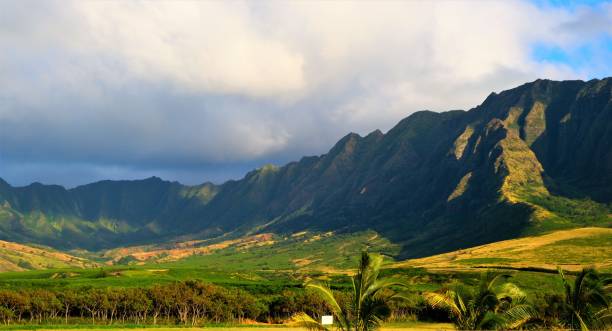 Makua Valley located within the Waianae Mtn range, Waianae, Oahu, HI Makua Valley is located on Oahu's leeward (West) coast in the foothills of the Waianae Mountains. Makua means parent in the Hawaiian language and legend has it that Makua Valley was the place where man was first created. Conversely, Hawaiians consider the valley to be the point from where souls depart for the afterlife once the human form has been cast off. For this reason one can see many handmade memorials to the dead along the rocky cliffs lining the shore. waianae mountain range stock pictures, royalty-free photos & images