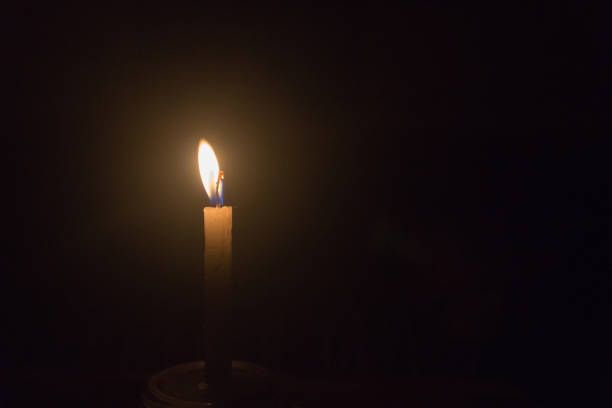 istock single light candle on the glass night in the dark background 1133916651