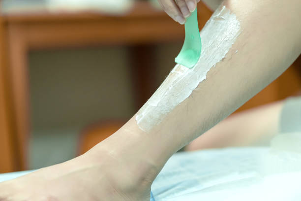 女性は脱毛クリームとヘラで脚を epilating。スクラブヘア除去クリーム。 - shaving human leg female shaving cream ストックフォトと画像
