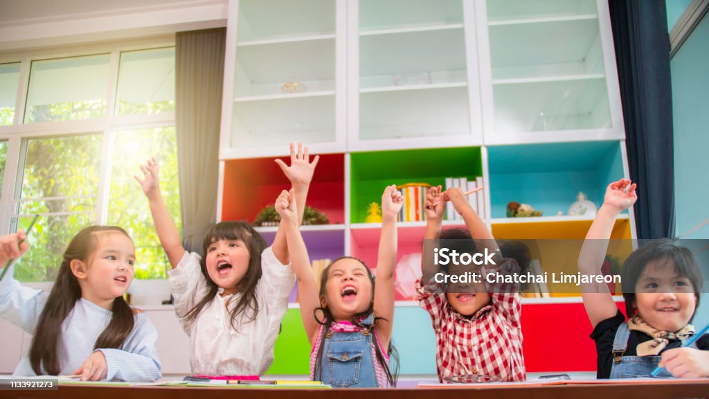 Group of multi-ethnic five little kids children African American, asian and Caucasian happiness together with friend to draw colour pencil to full colour of picture in living room or class room Child Stock Photo