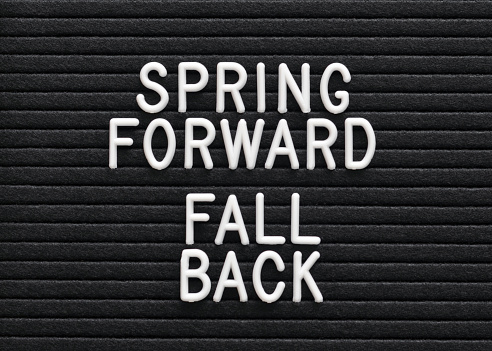 Closeup of a generic, mass produced sign board that says Spring Forward Fall Back symbolizing Daylight Savings Time.