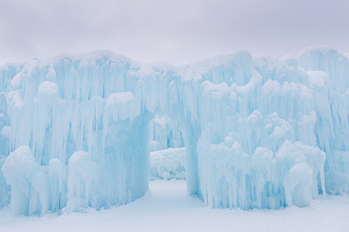 horizontal image of a  dreamy light blue ice castle with an arch open doorway on a beautiful snowy cold winter day with lots of copy space.