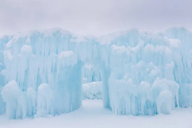 horizontal image of a  dreamy light blue ice castle with an arch open doorway on a beautiful snowy cold winter day with lots of copy space.