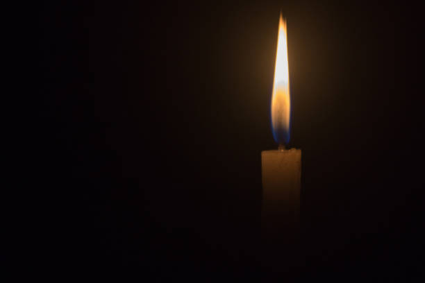 istock single light candle in the dark background 1133924598