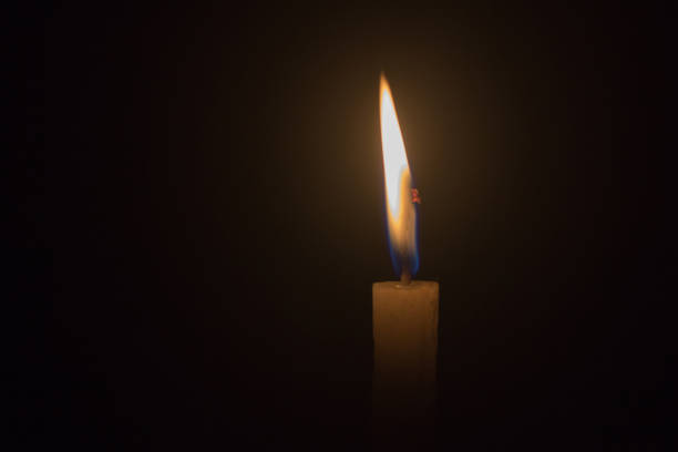 istock single light candle in the dark background 1133926804