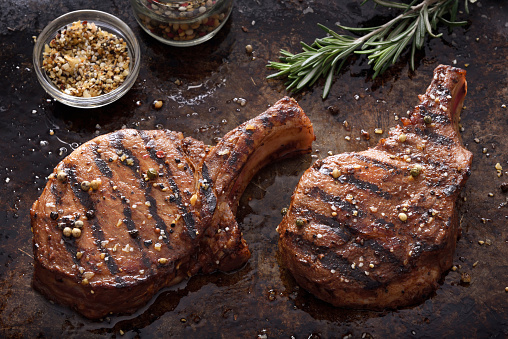 Juicy grilled pork chops with spices on a dark background
