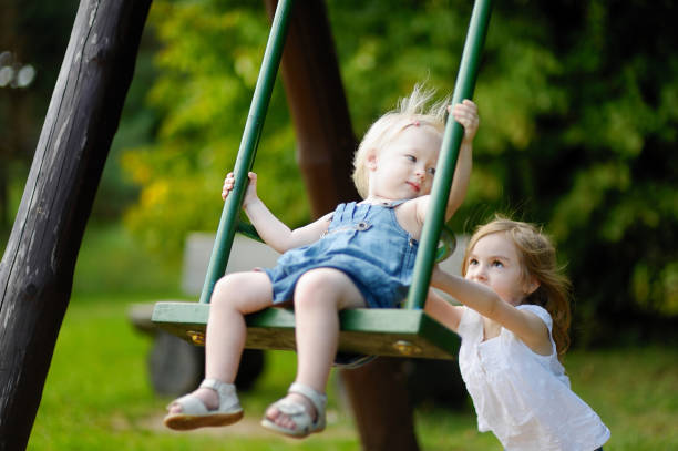 istock Two little sisters having fun on a swing 1133927731
