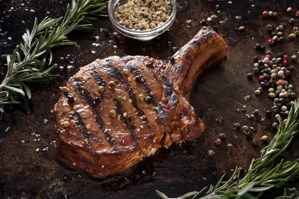 Juicy grilled pork chop with spices on a dark background