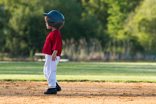 The profile of a young boy on base during a baseball game.