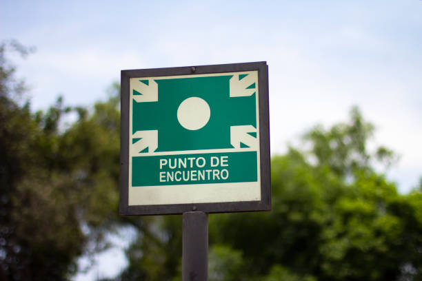 Street sign of "punto de encuentro" meeting point Street sign of "punto de encuentro" meeting point against green trees in spanish. Emergency evacuation assembly point signboard. punto stock pictures, royalty-free photos & images