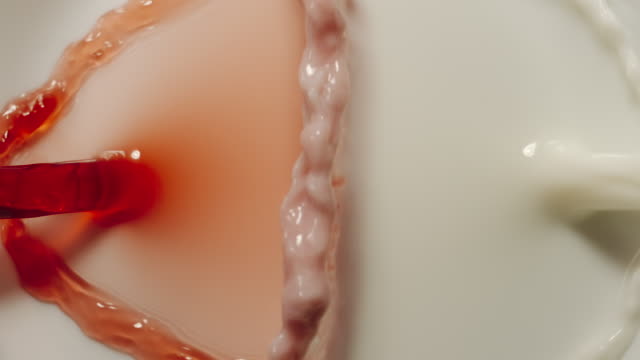 SLOW MOTION:  Cherry juice and milk mixing together - Top View