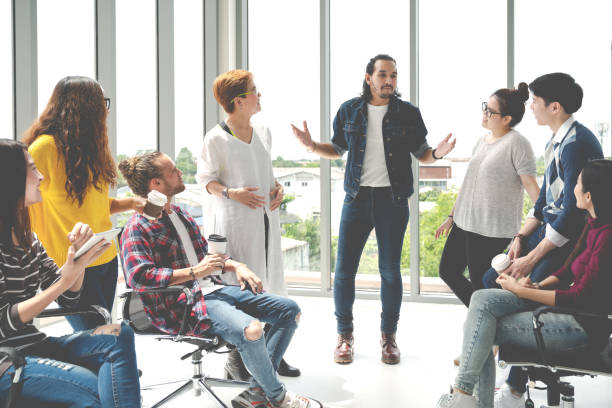 Attractive young multiethnic group talking at relax zone in coffee break time at office. Young asian hipster man sharing lifestyle idea to staff friends with fun and happy in happy workplace concept. atractivo grupo multiétnico joven hablando en la zona de relajación en tiempo de pausa de café en la oficina. joven asiático hipster hombre compartiendo estilo de vida idea a personal amigos con diversión y feliz en el concepto de lugar de trabajo fel
