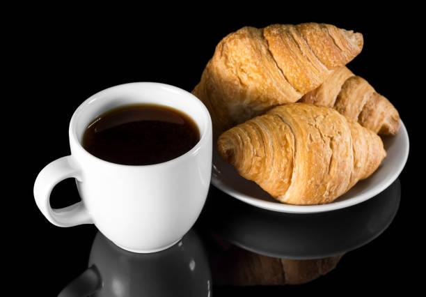istock Cup of coffee with croissants black reflective background. 1133944448