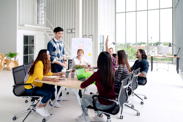 istock Group of young asian creative team talking, smile and laugh brainstorming, sharing or training on meeting or workshop at office. Happy asian workplace sitting attentive together in rear view concept. 1133946139