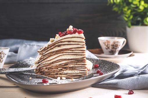 A slice of chocolate crepe cake on rustic background