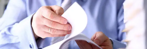 Photo of Clerk arm bend over pages in pile of documents closeup