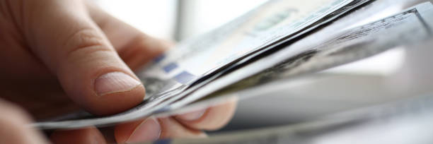 istock Male arm count hundred dollar bills closeup 1133953680