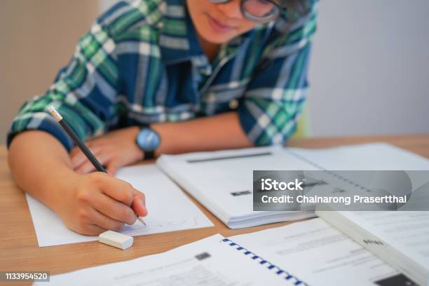 Close Up Young Asian Student Girl Using Pencil For Writing Formula Of Calculus On Paper For Do Homework In Library Silent Zone With Textbook Campus Lifestyle Concept Stock Photo - Download Image Now