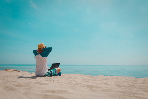 istock relaxed young man working on laptop at beach 1133954817