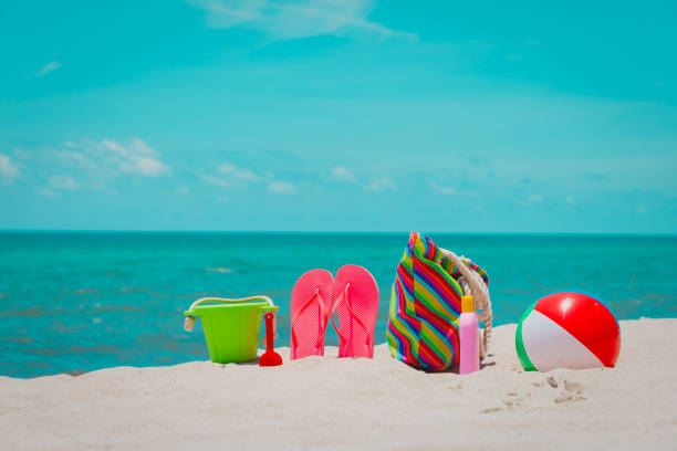 bag, suncream, toys and flip flops on beach, family vacation