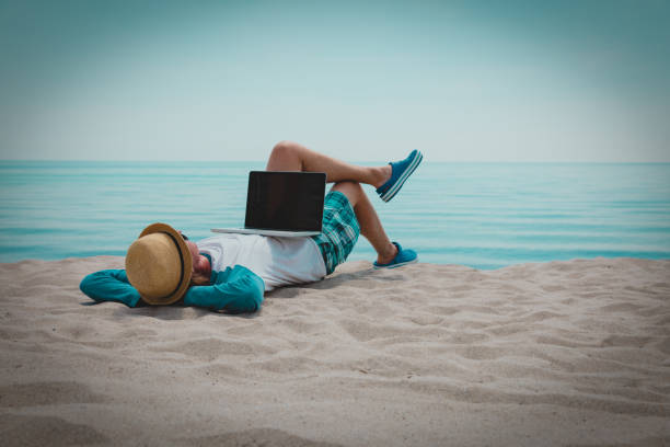 istock relaxed young man working on laptop at beach 1133956209