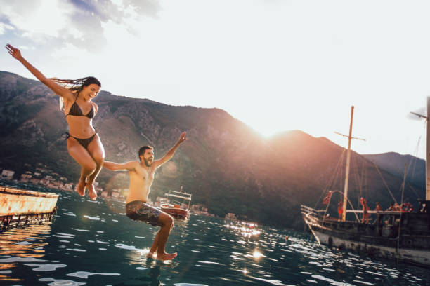istock Young couple jumping from a pier into the water 1133963959