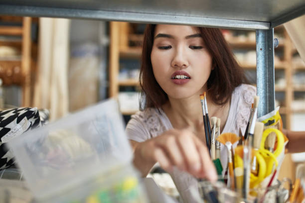 istock Female owner searching paintbrush on shelf 1133965643