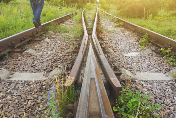 istock Man is standing on old rusty railway lines with grey stone chippings. Natural industrial background texture. 1133966669
