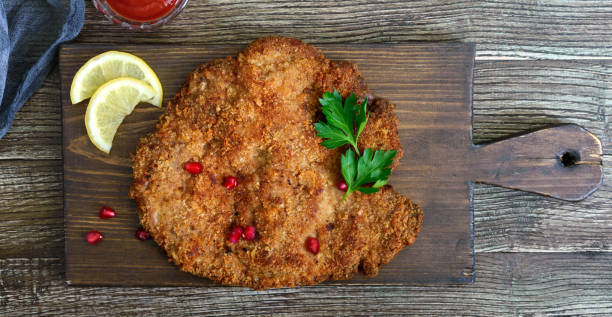 grande cotoletta viennese su sfondo ligneo. piatto di carne. vista dall'alto, lay piatto. - viennese schnitzel foto e immagini stock