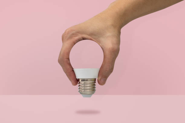 istock Hand holding a light bulb shape isolated on pink background, minimal idea 1133968968