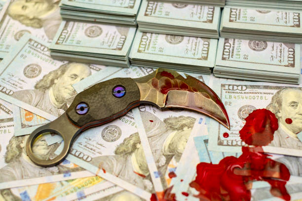 istock karambit knife on stack bundles of 100 US dollars banknotes bloody 1133970432