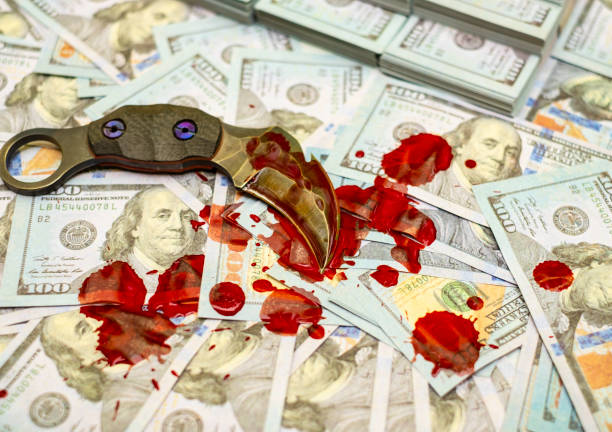 istock karambit knife on stack bundles of 100 US dollars banknotes bloody 1133970436