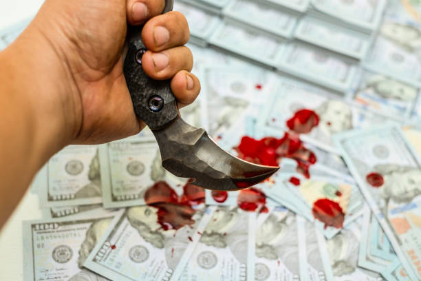 istock karambit knife on stack bundles of 100 US dollars banknotes bloody 1133970473