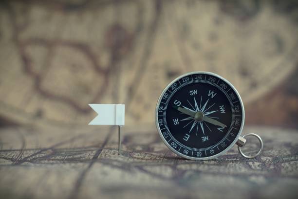 istock Old compass and flag marking pins on blur vintage map background, journey planning concept, copy space 1133971937