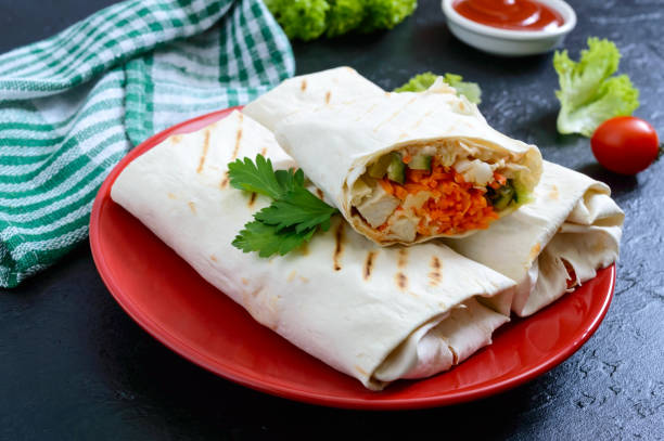 istock Delicious shawarma sandwich on a black background. Burritos wraps with grilled chicken and vegetables, greens. Fajitas, pita bread. Traditional Middle Eastern appetizer. Mexican cuisine 1133972779