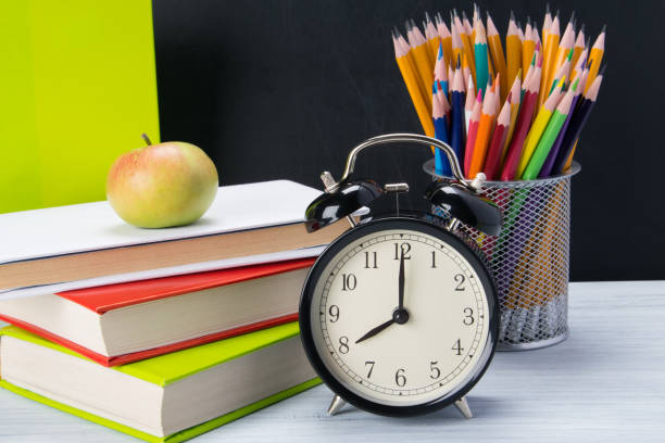 istock on the table books for learning, a light snack Apple and alarm clock 1133976454