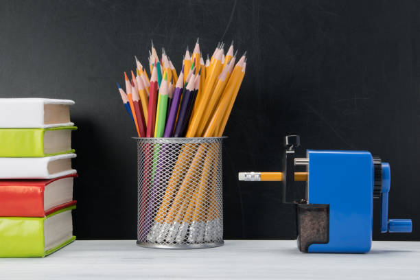 istock pencils in a glass, books and sharpener, standing on a light table on a black background 1133976469