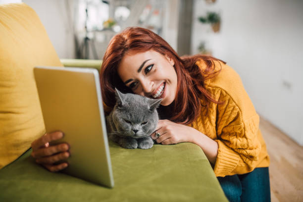 istock Happy girl hugging cat and looking at digital tablet 1133976555