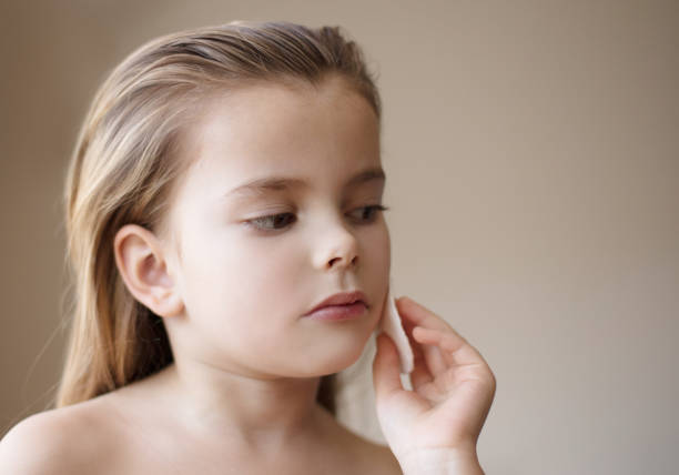 Clean skin is very important. Little girl cleaning her face. Close up.
