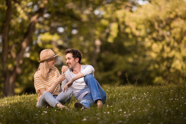 istock Young happy couple talking while relaxing in grass at the park. 1133980113