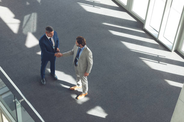 istock Businessmen shaking hands in office building 1133980146
