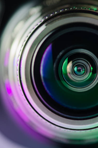 istock Camera lens and backlight are purple-green. Vertical photo 1133983232